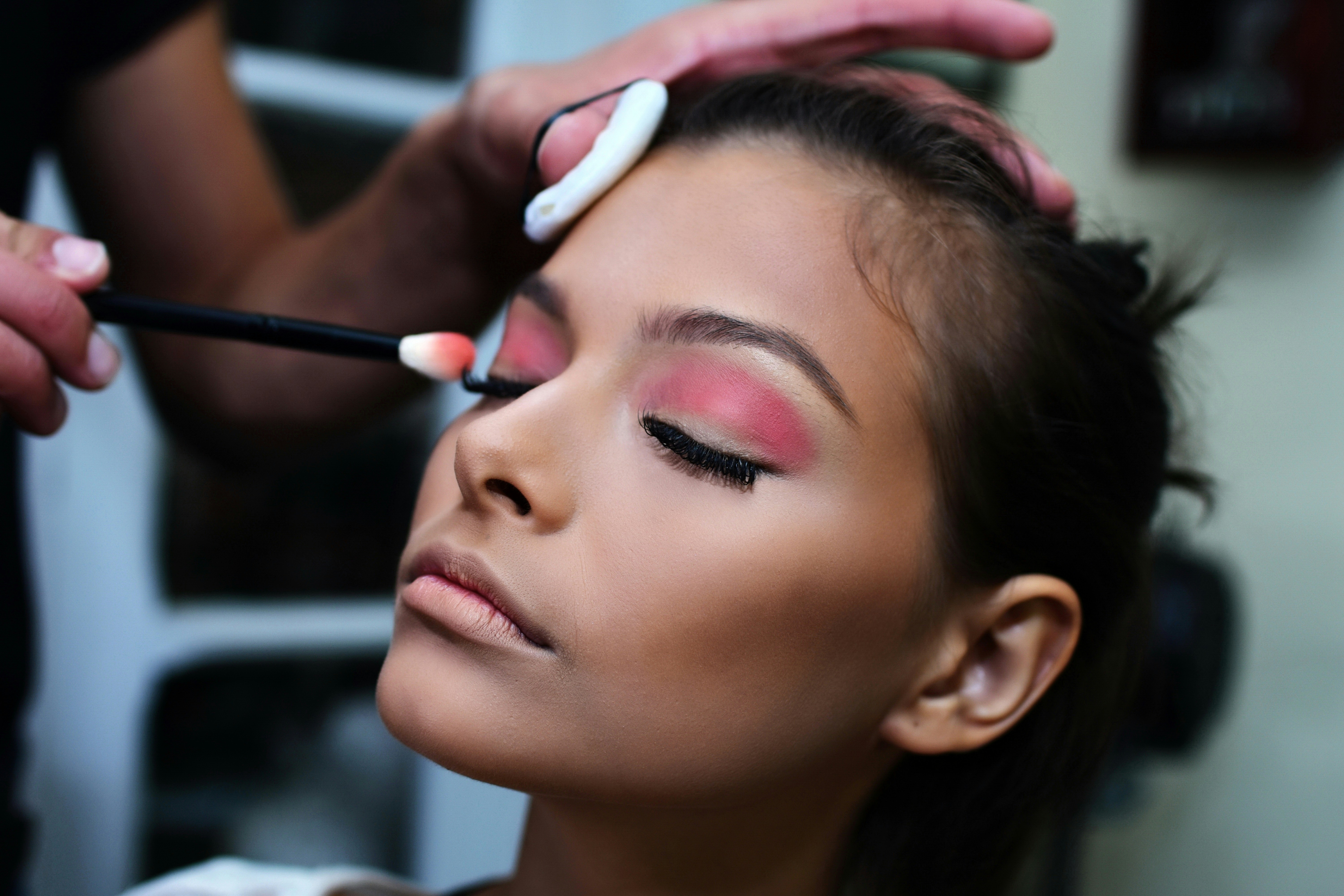 A woman getting red eye shadow applied